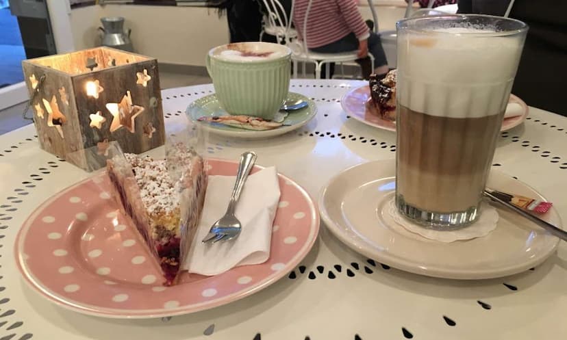 Kaffee und Kuchen auf einem gedeckten Tisch. Eine Kerze steht dabei.