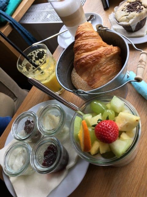 Leckeres Frühstück im Café Juli. Man sieht ein Croissant, Früchte und diverse Brotaufstriche